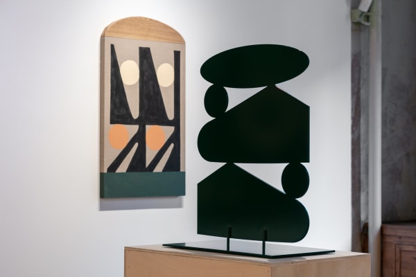 Installation view showing a close-up of the back of Non Destructive Time Stretch Tall Stack with Storm King Trips Festival on the wall in the background.