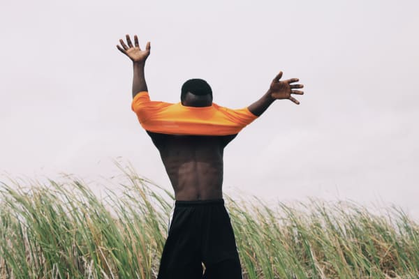 Man in an orange t-shirt and open arms photographed by Ghanaian Nana Yaw Oduro