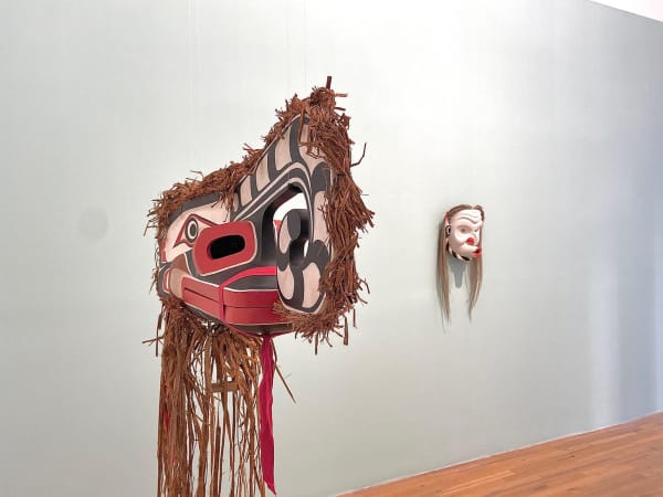 Beau Dick (1994) “Crooked Beak” (foreground). Red Cedar, cedar bark and acrylic paint, 12 x 8 x 34 inches.