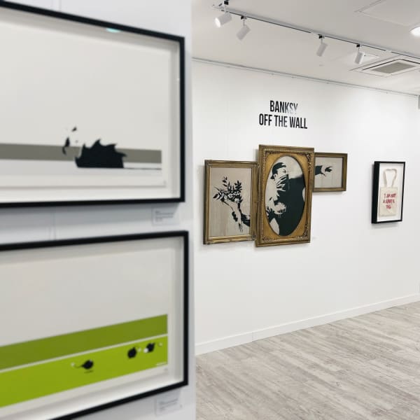 Gallery display featuring Banksy's 'Flower Thrower' and other artworks