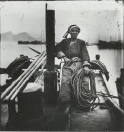 Black and white photograph of Chinese skipper sitting on dock