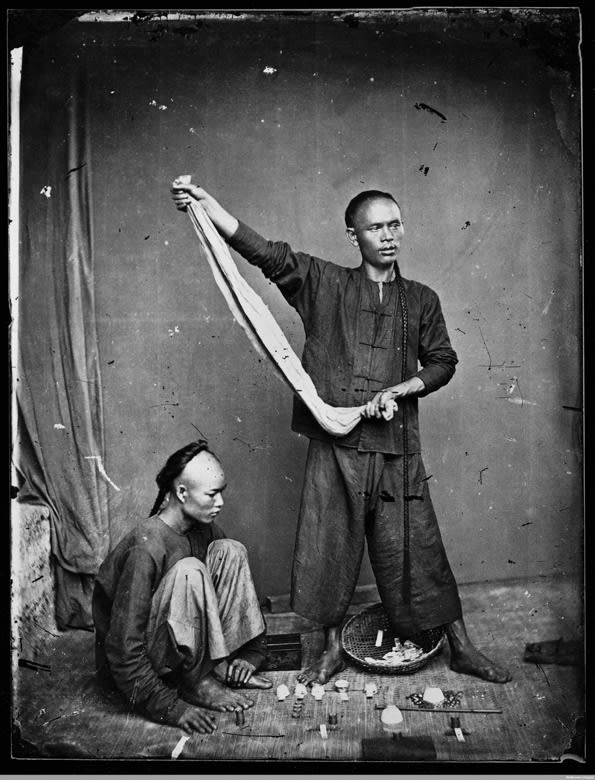 Black and white photograph of two men gambling on the street of Canton