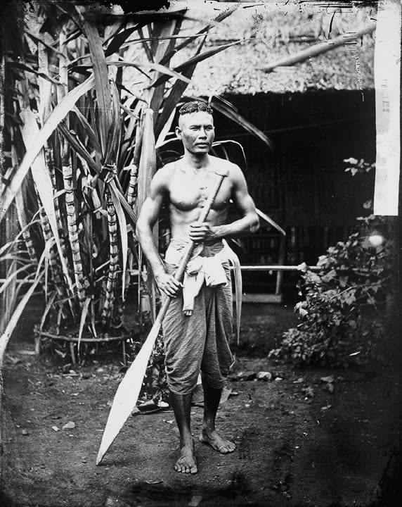 Black and white photo of young Cambodian Man with large paddle