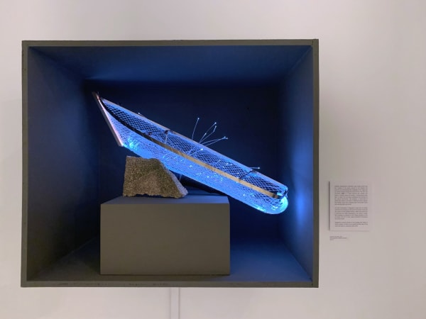 A glowing blue sculpture of a boat in a niche of a wall