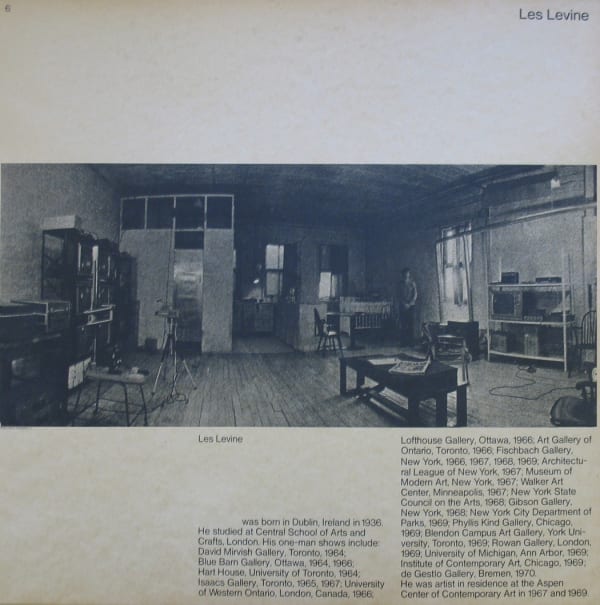 Black and white photograph of Les Levine in his studio with text underneath