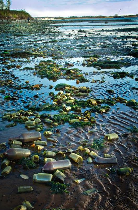Photograph of a waterway littered with discarded bottles and cans