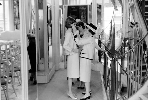 Black and white photograph of Coco Chanel with a model preparing for the new collection on the second floor of House of Chanel in Paris