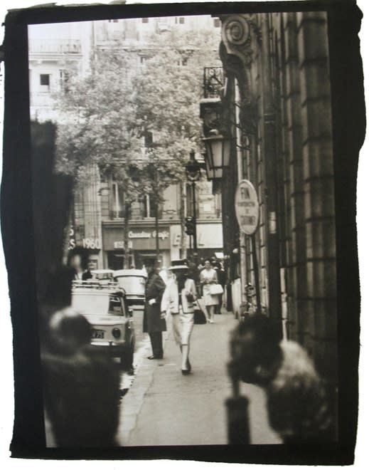 Black and white photograph with black border of Coco Chanel walking from the Ritz to the House of Chanel