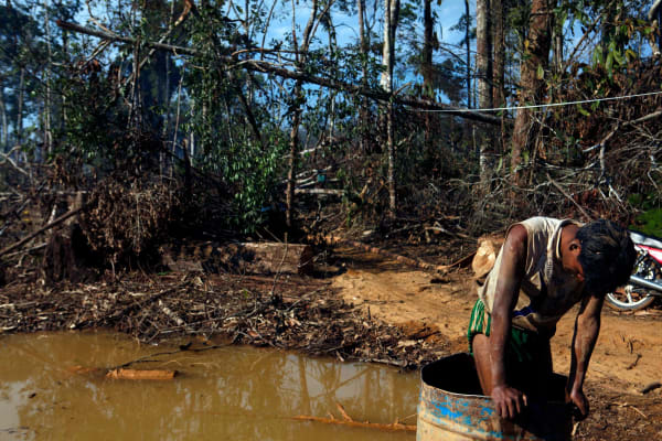 A gold miner stands in a barrel filled with mercury in order to separate the gold from the excavation matter, in the mining area of Lamal, Madre de Dios region, Peru