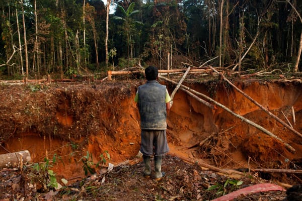 A gold miner stands above a ravine in the mining city of Lamal