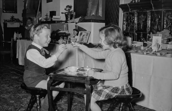 Black and white photograph of two children sitting at a table, smiling