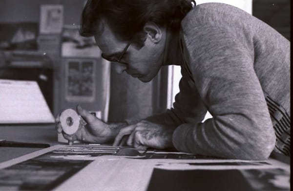 A man holding tape leaning over a table while drawing.