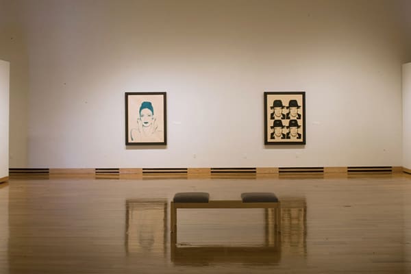 Installation view of two framed artworks by Andy Warhol (portrait in green, multiple portrait in black)