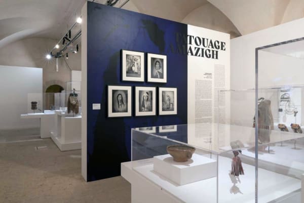Installation view of an exhibition at a museum with artifacts in vitrines and photographs on a wall