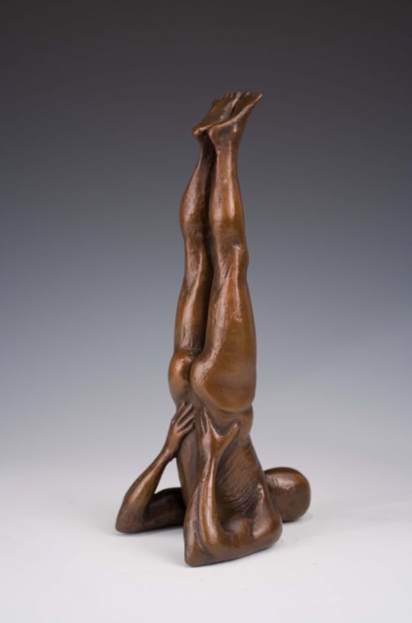 A bronze sculpture of a man doing a yoga pose