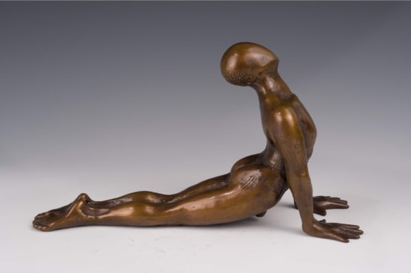 a bronze sculpture of a man doing a yoga pose