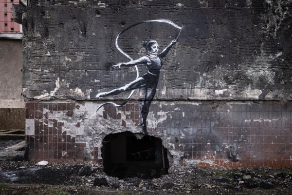 Banksy’s 2022 Gymnast with a Ribbon mural in Irpin shows graceful movement amid urban destruction.