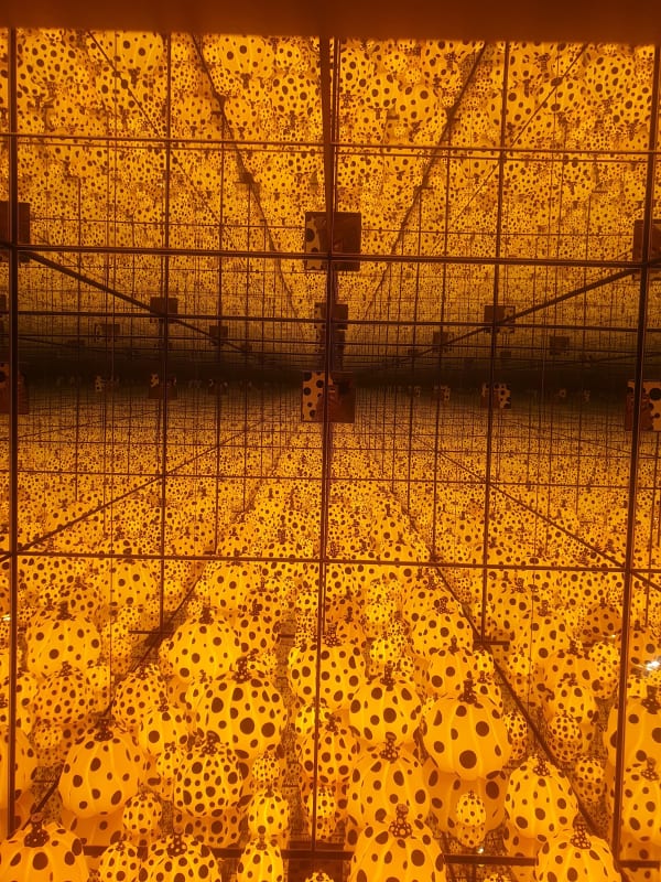 Yayoi Kusama, The Spirits of the Pumpkins Descended into the Heavens, 2021, immersive installation with glowing yellow pumpkin sculptures and mirrored reflections