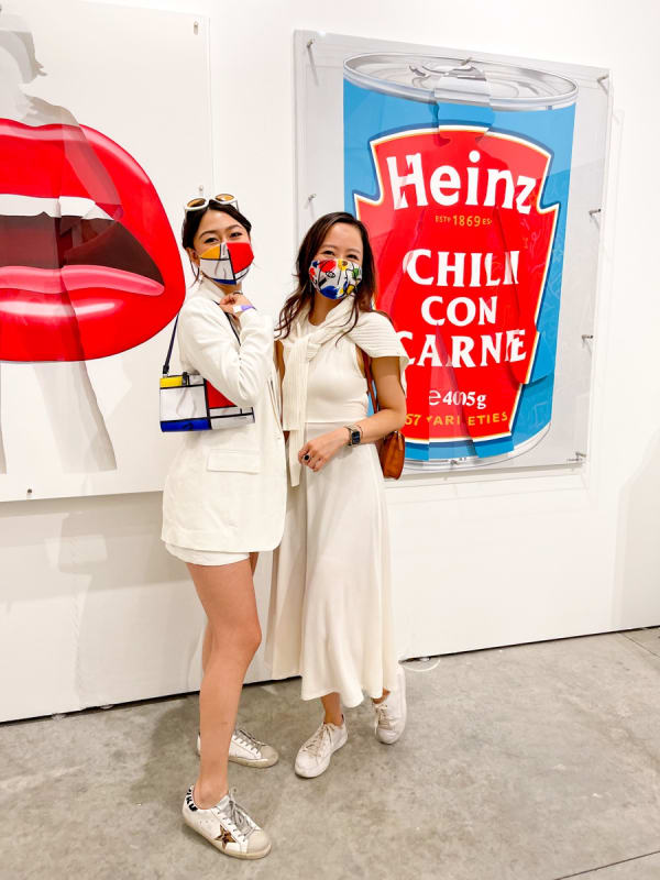 Women posing in front of paintings displayed at Carousel Fine Art's booth at the art fair, Context Art Miami 2021.
