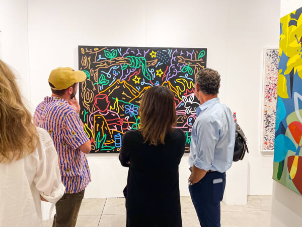 People staring at paintings displayed at Carousel Fine Art's booth at the art fair, Context Art Miami 2021.