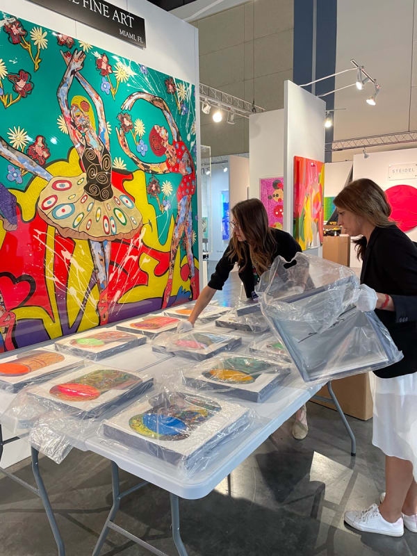 Women setting up table of posters at Carousel Fine Art's booth at the Palm Beach Show art fair, 2022.