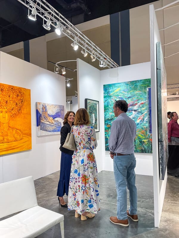People in front of the paintings displayed at Carousel Fine Art's booth at the Palm Beach Show art fair, 2023.