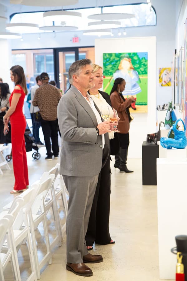 People staring at paintings displayed at Carousel Fine Art's gallery space in Buckhead Village, Atlanta during the Caroline Dechamby Retrospective.