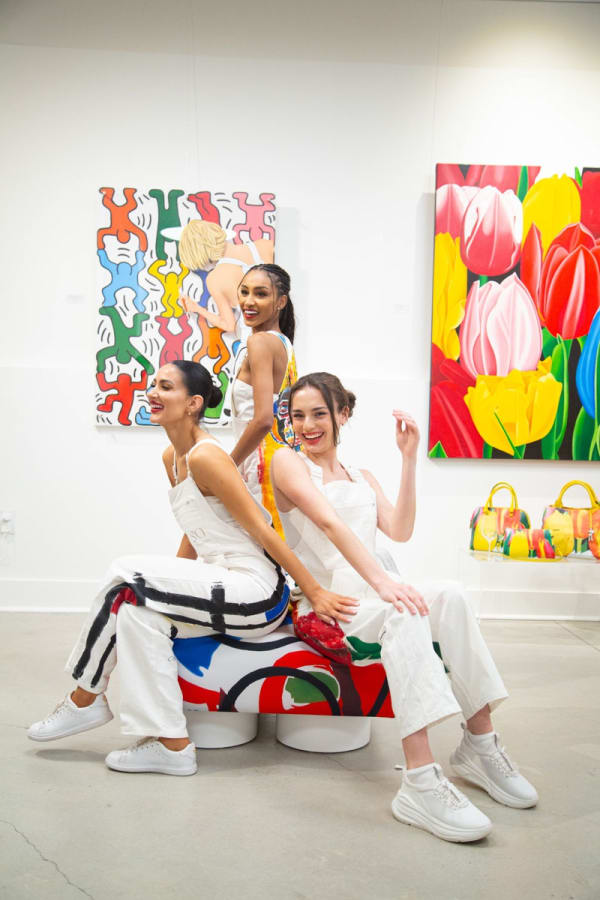 Models posing on furniture pouf at Carousel Fine Art's gallery space in Buckhead Village, Atlanta during the Caroline Dechamby Retrospective.