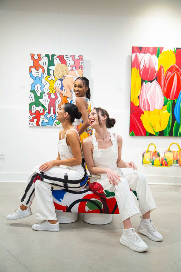 Models posing on furniture pouf at Carousel Fine Art's gallery space in Buckhead Village, Atlanta during the Caroline Dechamby Retrospective.