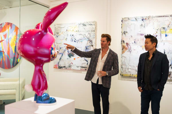 Man pointing at sculpture and paintings displayed in Carousel Fine Art's Miami gallery space during the Grand Opening.