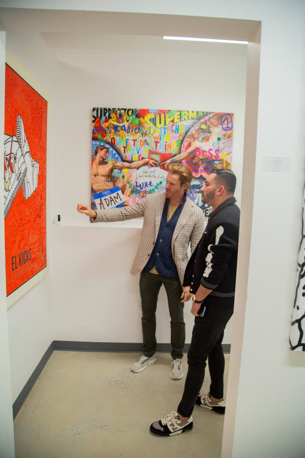 Men staring at paintings displayed at Carousel Fine Art's new gallery space in Buckhead Village, Atlanta during an event for their grand opening.