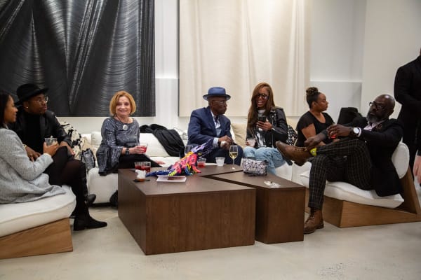 People on the couch at Carousel Fine Art's new gallery space in Buckhead Village, Atlanta during an event for their grand opening.