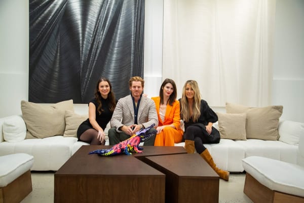People posing on the couch at Carousel Fine Art's new gallery space in Buckhead Village, Atlanta during an event for their grand opening.
