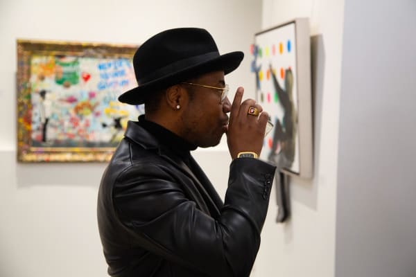 Man staring at paintings displayed at Carousel Fine Art's new gallery space in Buckhead Village, Atlanta during an event for their grand opening.