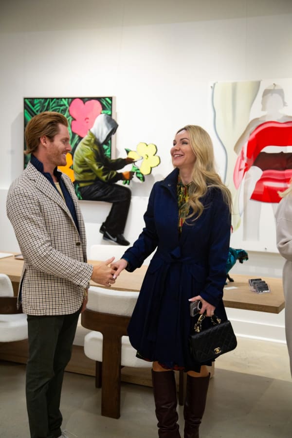 People staring at paintings displayed at Carousel Fine Art's new gallery space in Buckhead Village, Atlanta during an event for their grand opening.