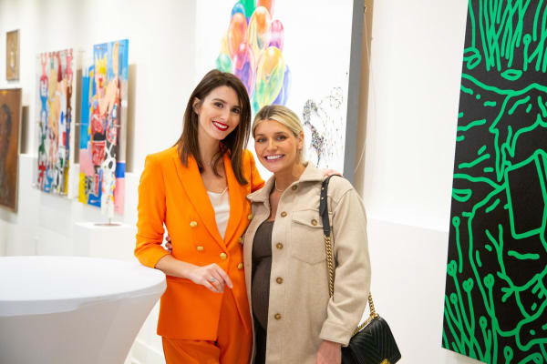 People staring at paintings displayed at Carousel Fine Art's new gallery space in Buckhead Village, Atlanta during an event for their grand opening.