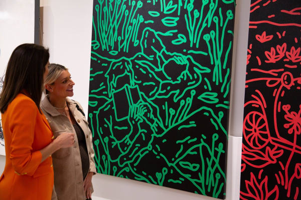 People staring at paintings displayed at Carousel Fine Art's new gallery space in Buckhead Village, Atlanta during an event for their grand opening.