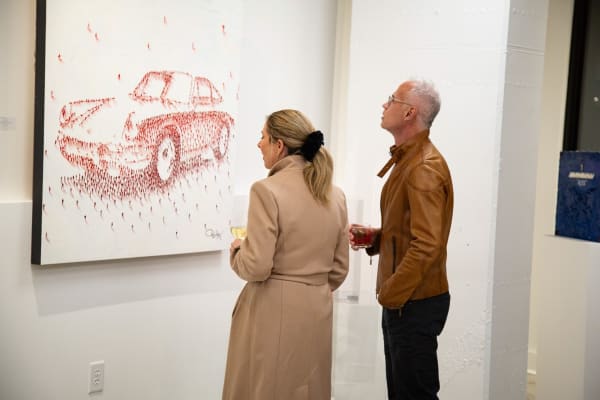 People staring at paintings displayed at Carousel Fine Art's new gallery space in Buckhead Village, Atlanta during an event for their grand opening.
