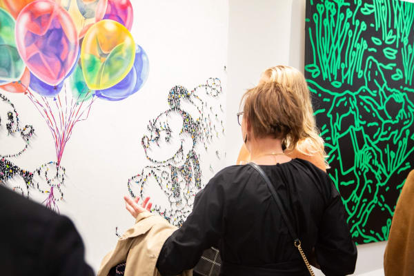 People staring at paintings displayed at Carousel Fine Art's new gallery space in Buckhead Village, Atlanta during an event for their grand opening.