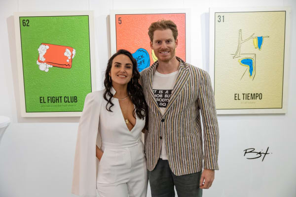 People posing in front of Cayla Birk's artworks displayed in Carousel Fine Art's Miami location for the Cayla Birk exhibition, "It's in the Cards."