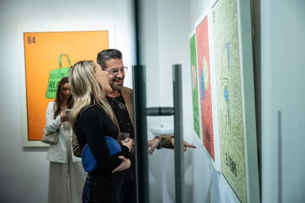 People laughing in front of paintings by Cayla Birk in Carousel Fine Art's Miami location for the Cayla Birk exhibition, "It's in the Cards."