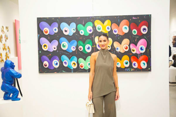 Woman posing in front of painting by John Westbay in Carousel Fine Art's Atlanta gallery space during the spotlight exhibition for John Westbay titled "Love, Outside the Lines."