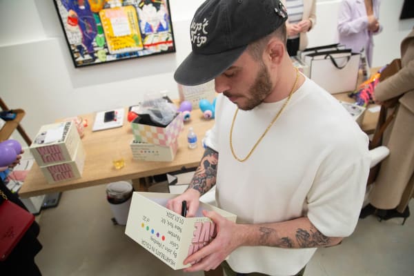 Artist John Westbay signing heart object during the spotlight exhibition for John Westbay titled "Love, Outside the Lines."