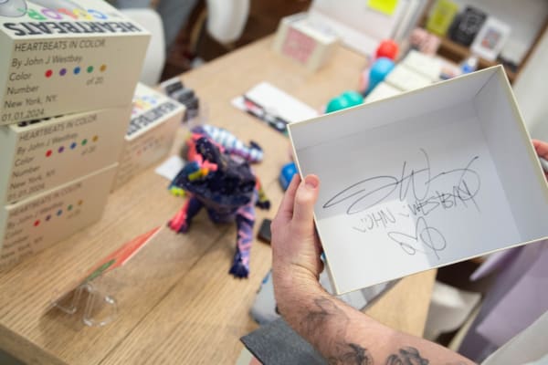 Artist John Westbay signing box during the spotlight exhibition for John Westbay titled "Love, Outside the Lines."