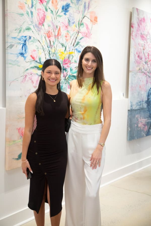 People posing in front of Eric Alfaro's paintings displayed in Carousel Fine Art's Buckhead Village location during the Eric Alfaro exhibition "Spring Reverie."