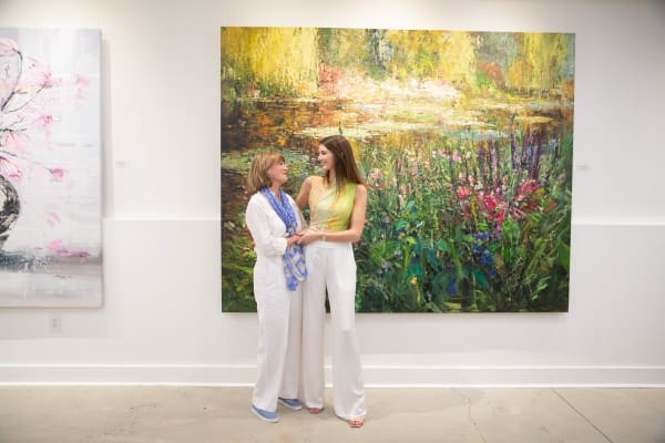 People posing in front of Eric Alfaro's paintings displayed in Carousel Fine Art's Buckhead Village location during the Eric Alfaro exhibition "Spring Reverie."