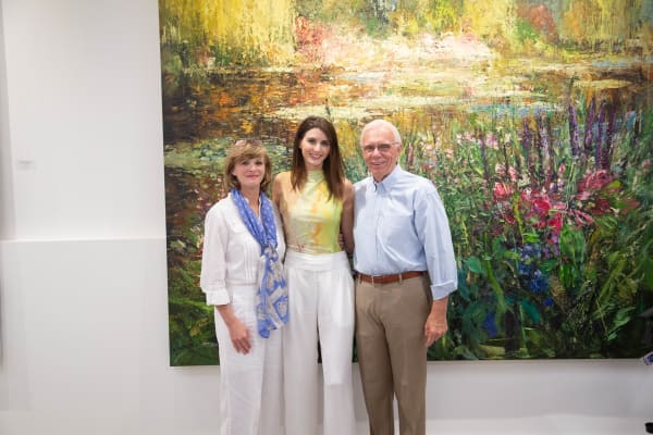 People posing in front of Eric Alfaro's paintings displayed in Carousel Fine Art's Buckhead Village location during the Eric Alfaro exhibition "Spring Reverie."