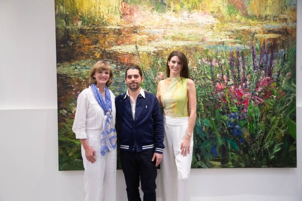 People posing in front of Eric Alfaro's paintings displayed in Carousel Fine Art's Buckhead Village location during the Eric Alfaro exhibition "Spring Reverie."