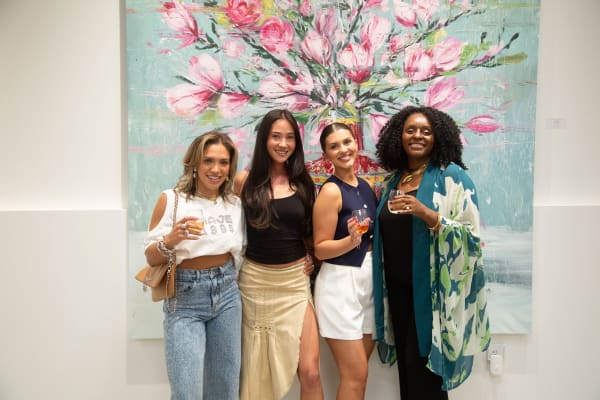 People posing in front of Eric Alfaro's paintings displayed in Carousel Fine Art's Buckhead Village location during the Eric Alfaro exhibition "Spring Reverie."