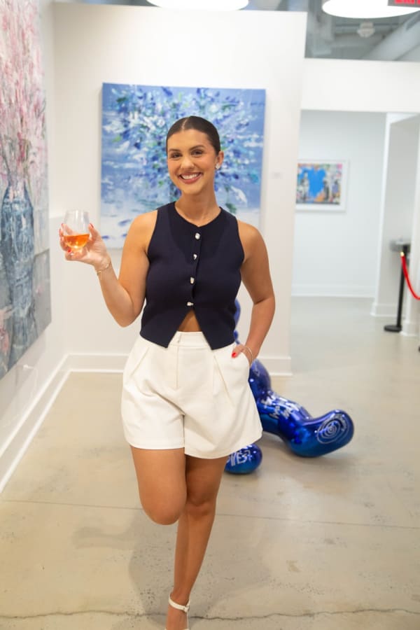 Woman posing in front of Eric Alfaro's paintings displayed in Carousel Fine Art's Buckhead Village location during the Eric Alfaro exhibition "Spring Reverie."